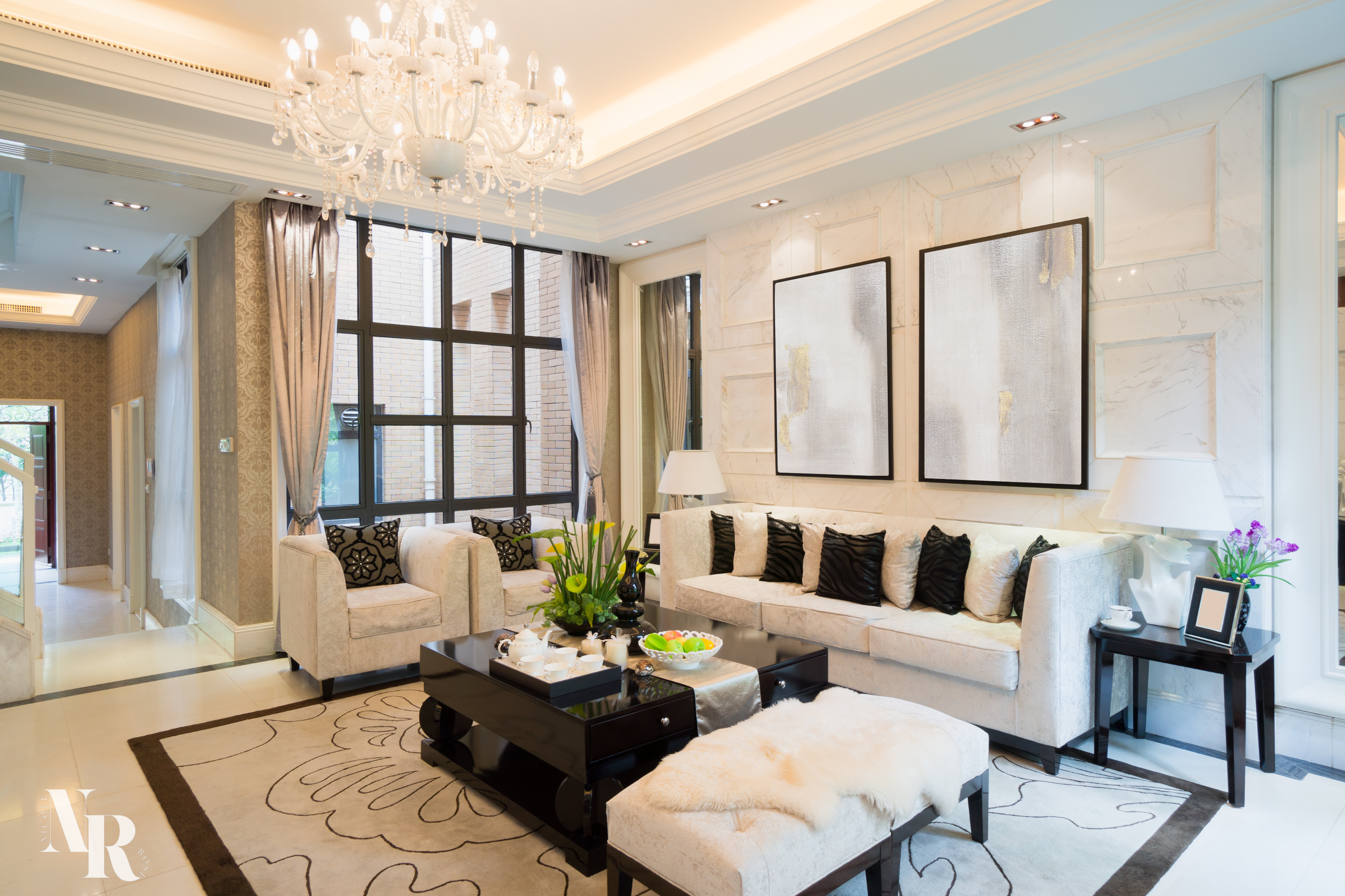 Nicole Rose Abstract Wall Art framed in a black wooden frame in a living room on top of a cream couch with brown pillows. The art is a blend of gold, cream, champagne colours and is a hand painted oil canvas image. Matches the luxury tones of the living room which has cream and brown decor